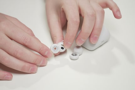 The headphones are made of two elements and look like a figure eight. One part contains the driver, the other (with the hole) directs music into the ear.