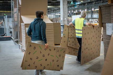 Aurel et Geri distribuent les nouveaux cartons dans la logistique.