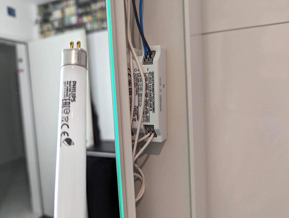 Un ballast électronique dans une armoire de toilette qui commande trois tubes.