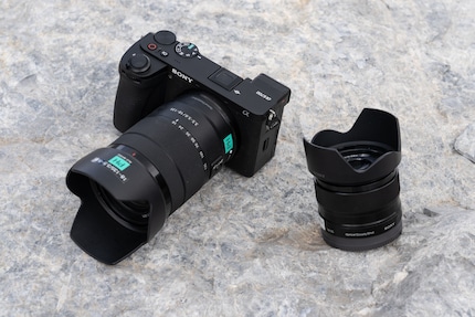 Die Sony A6700 sieht blockig aus, liegt aber gut in der Hand. Ich wähle ein 18-135 mm (an der Kamera) und ein 35 mm f/1.8 (rechts) – beide sind sehr leicht.