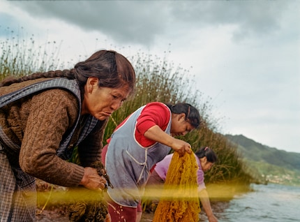 Due donne lavano le fibre appena tinte nel lago. I coloranti chimici rilasciano sostanze tossiche nell'ambiente, mentre i coloranti naturali si integrano perfettamente.